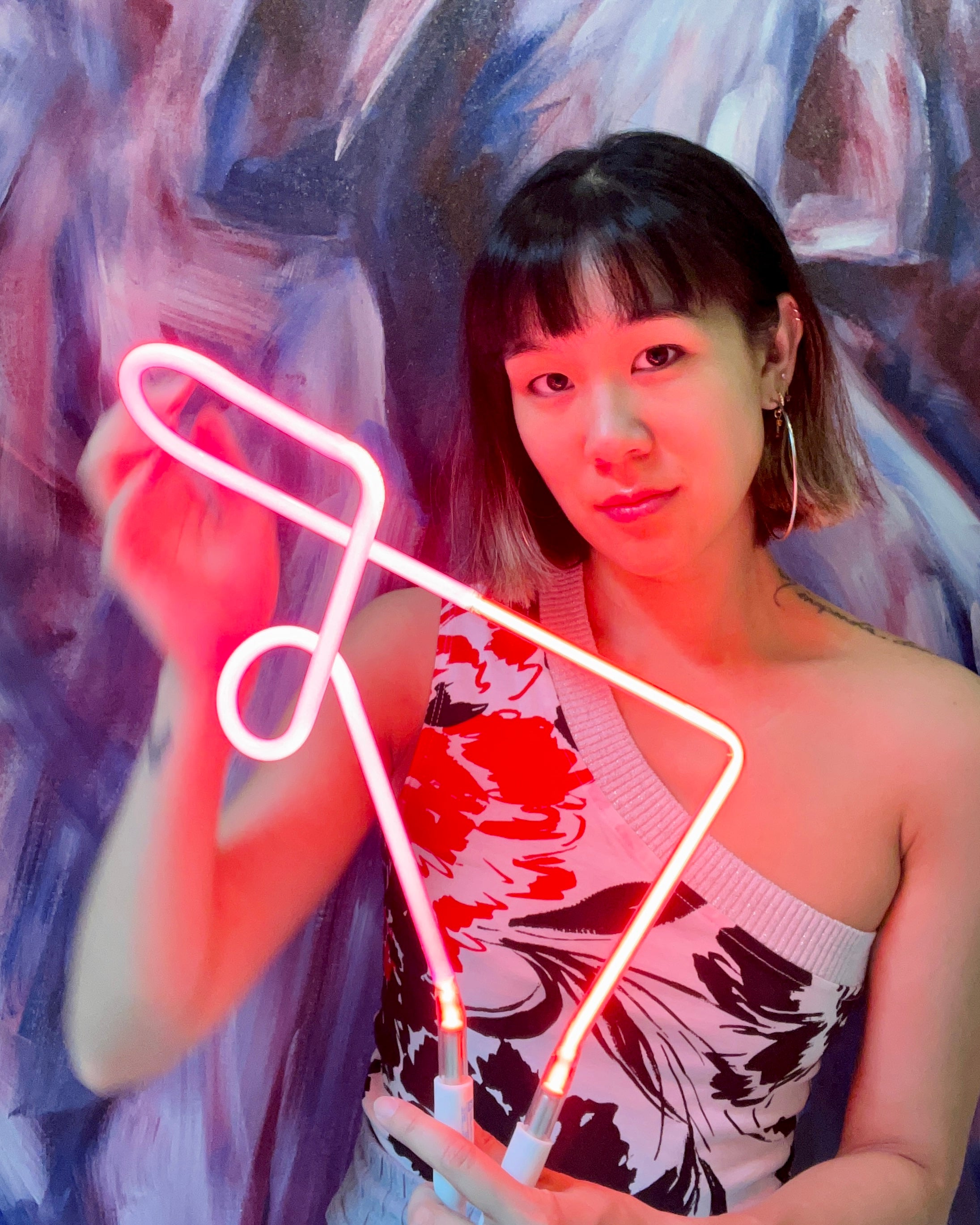 Bonnie holding an abstract neon art piece