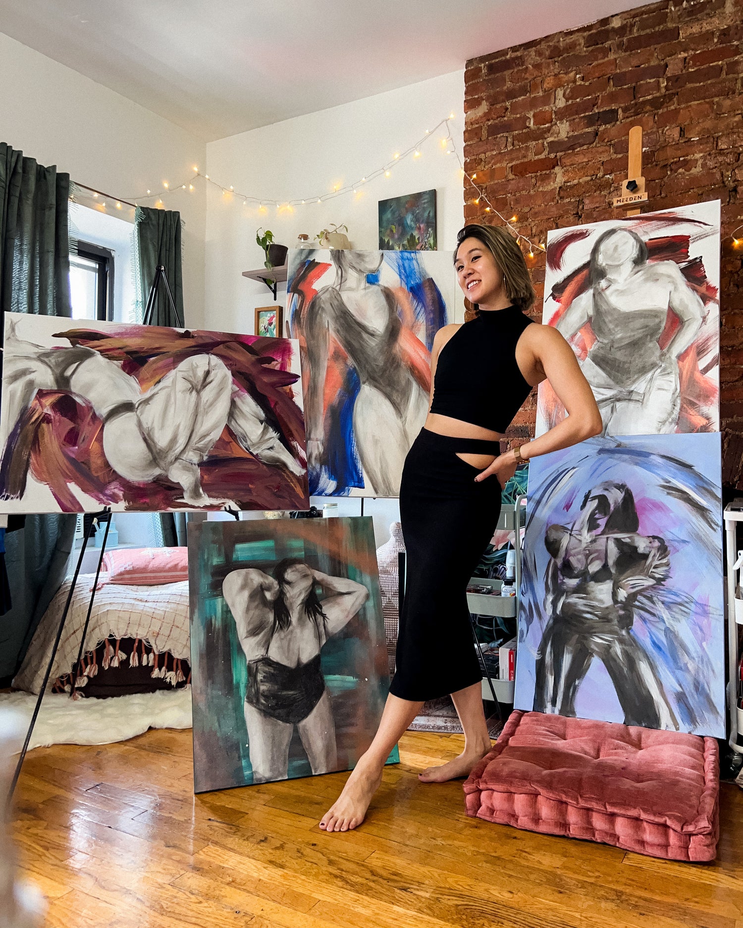 Bonnie standing and smiling in front of her paintings